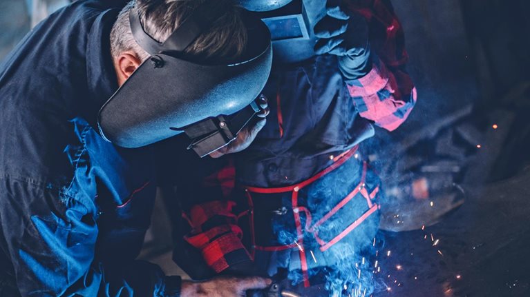 Man and woman welding together in workshop