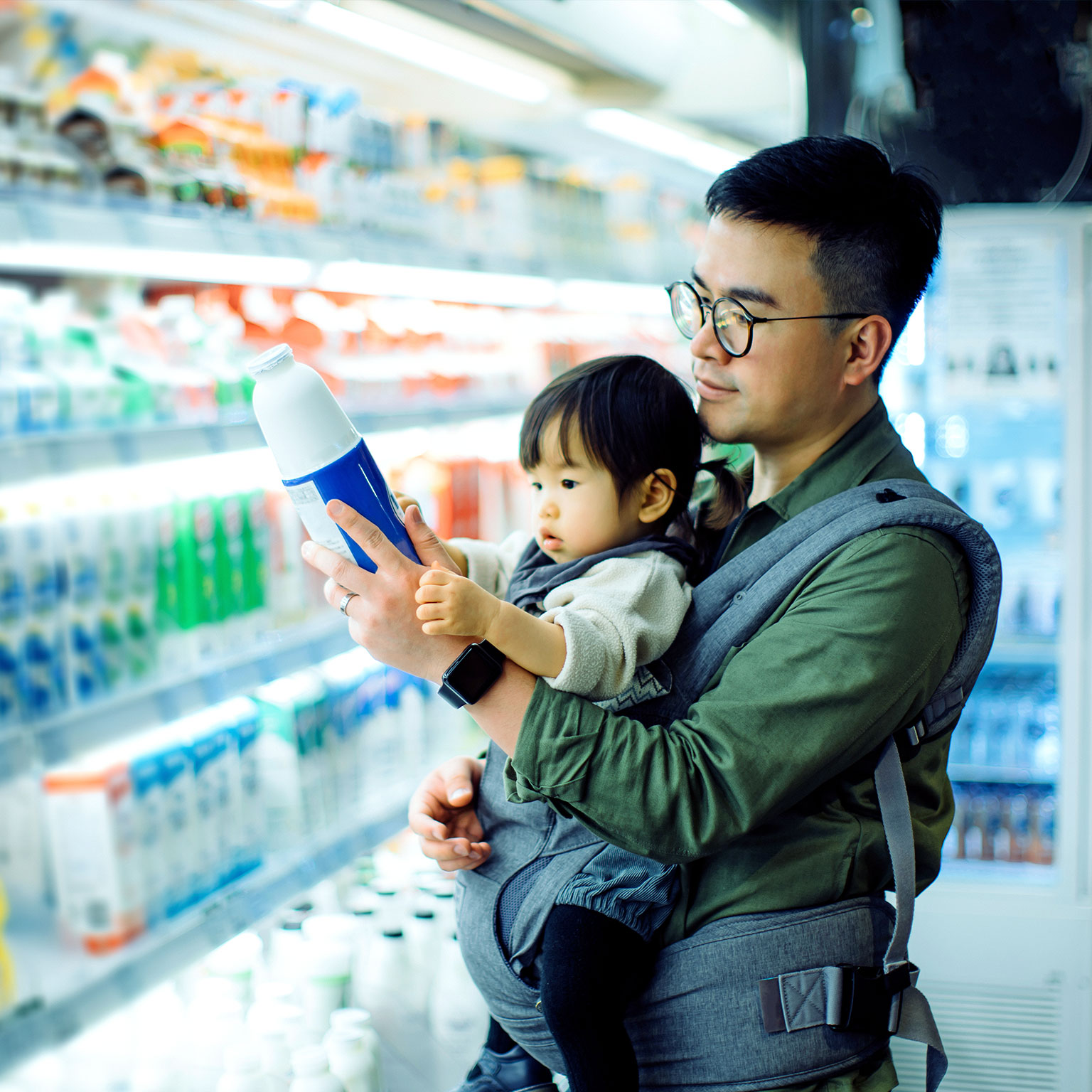 Young Asian father with daughter grocery shopping for dairy products in supermarket