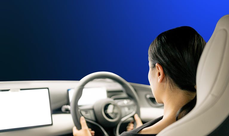 An Asian woman sits in the cockpit of a new energy car, operating a display with intelligent driving functions