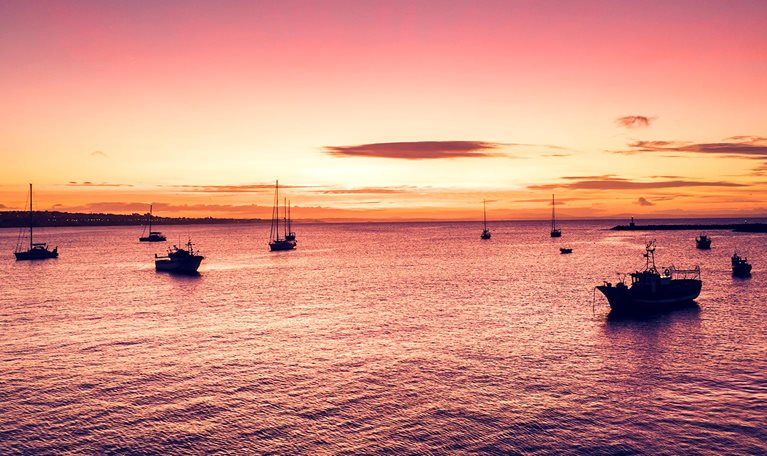 Aerial view of boats and ships in the sea near the port in Cascais, Portugal during sunset