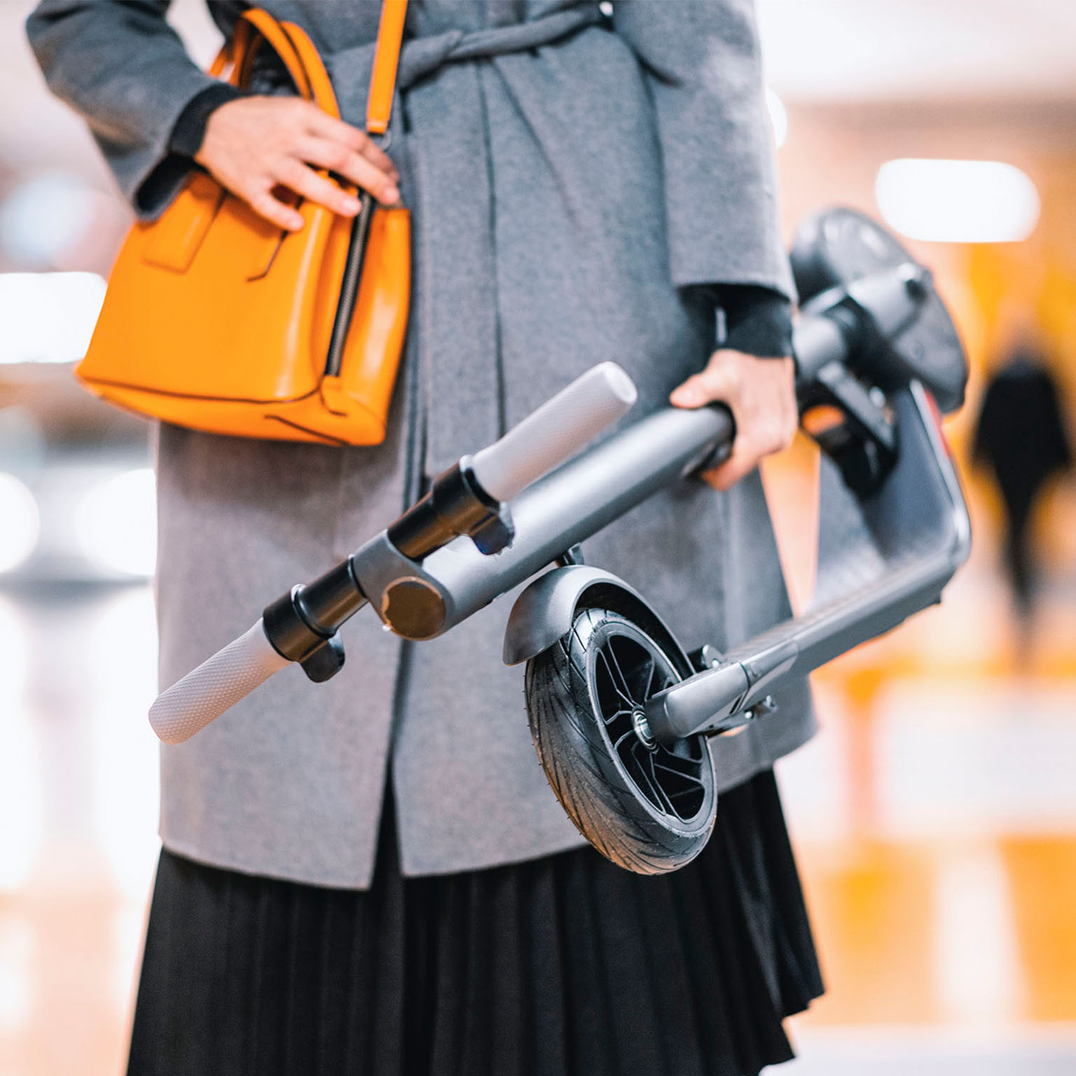Modern businesswoman carrying an e-scooter while heading to work