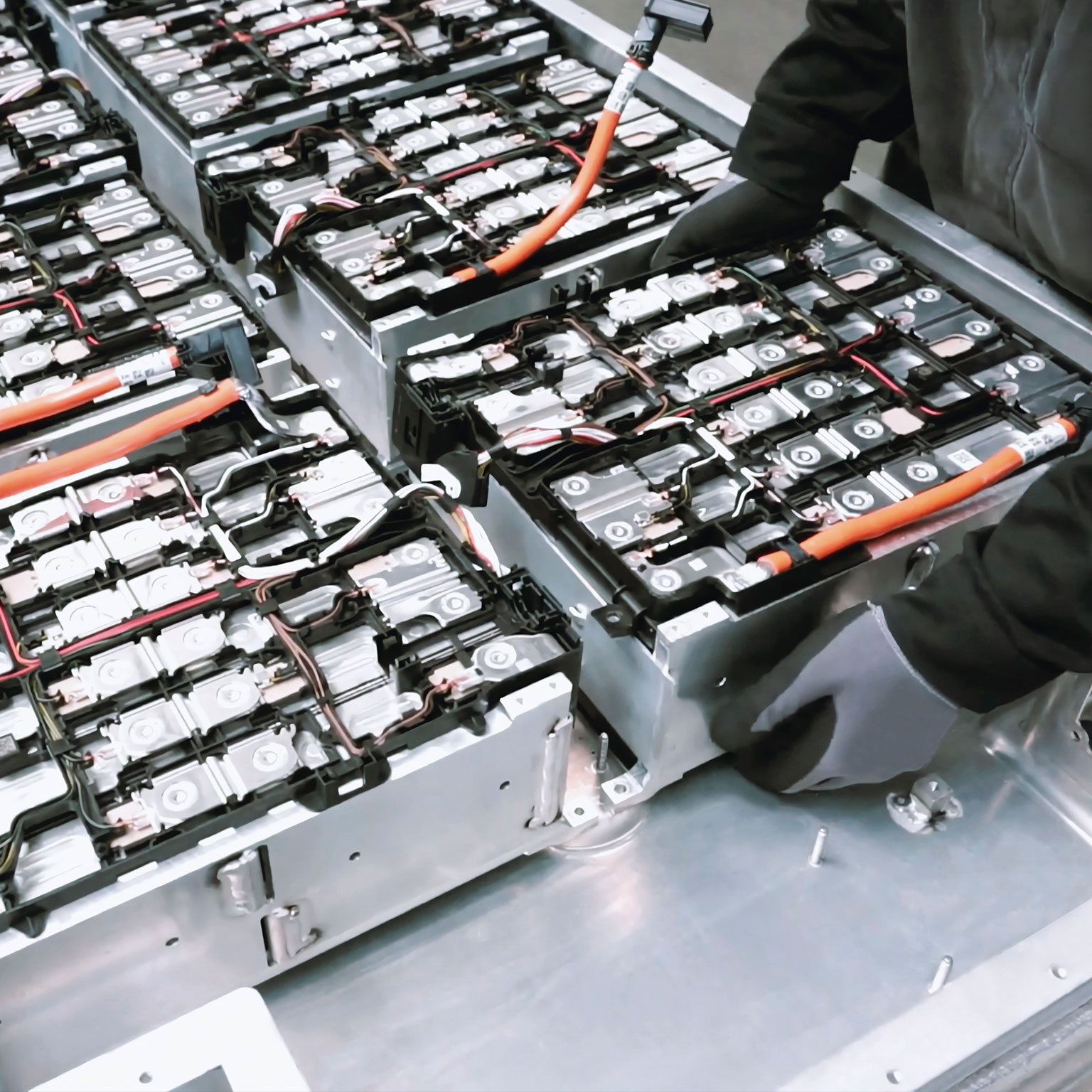 Close-up of two mechanics repairing the battery of an electric car in a car workshop