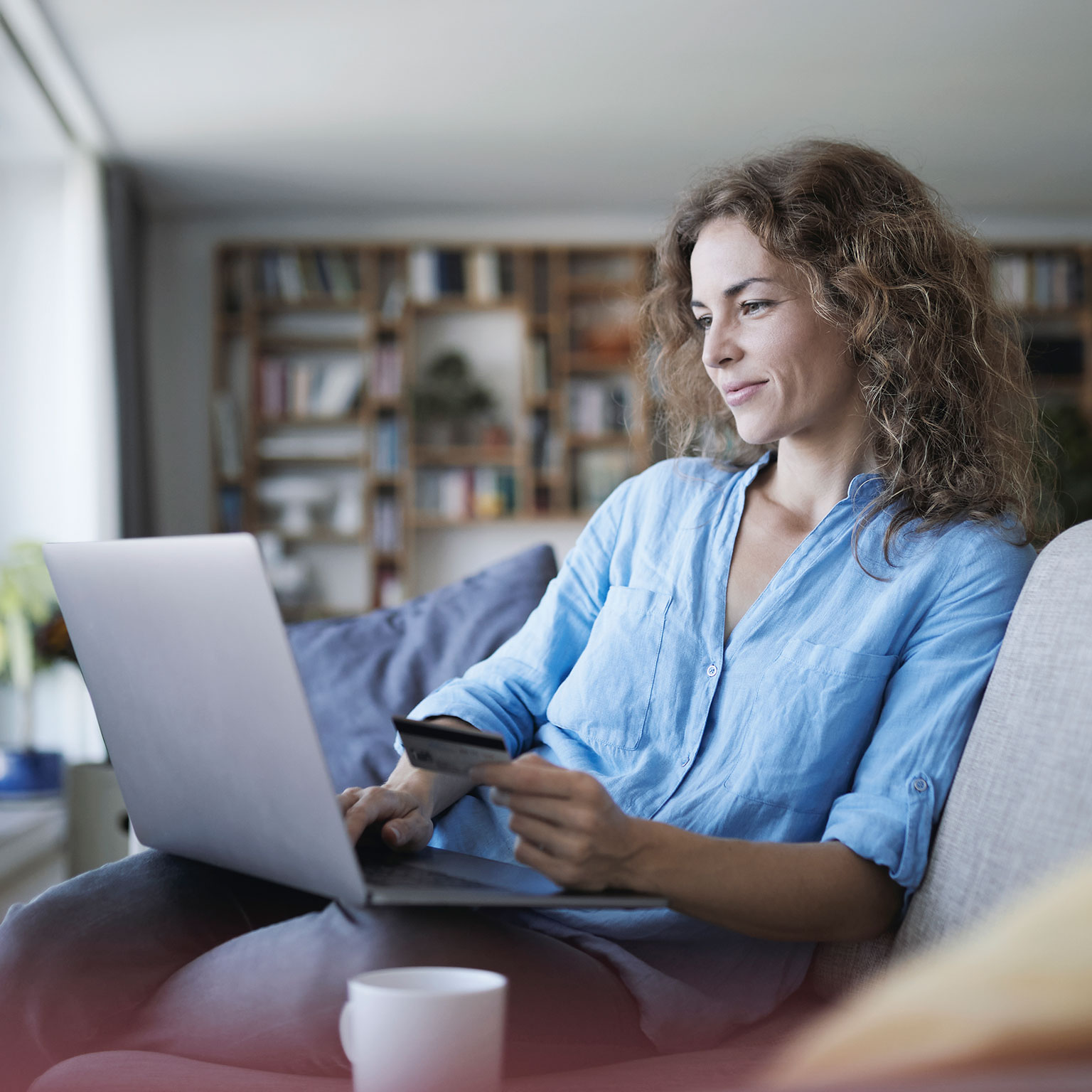 Smiling woman doing online shopping on laptop at home 