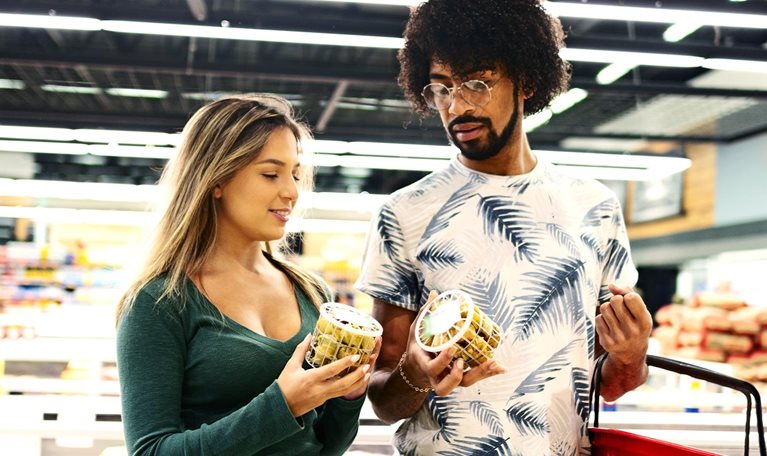 Young couple shopping and discussing purchase decision in grocery store.