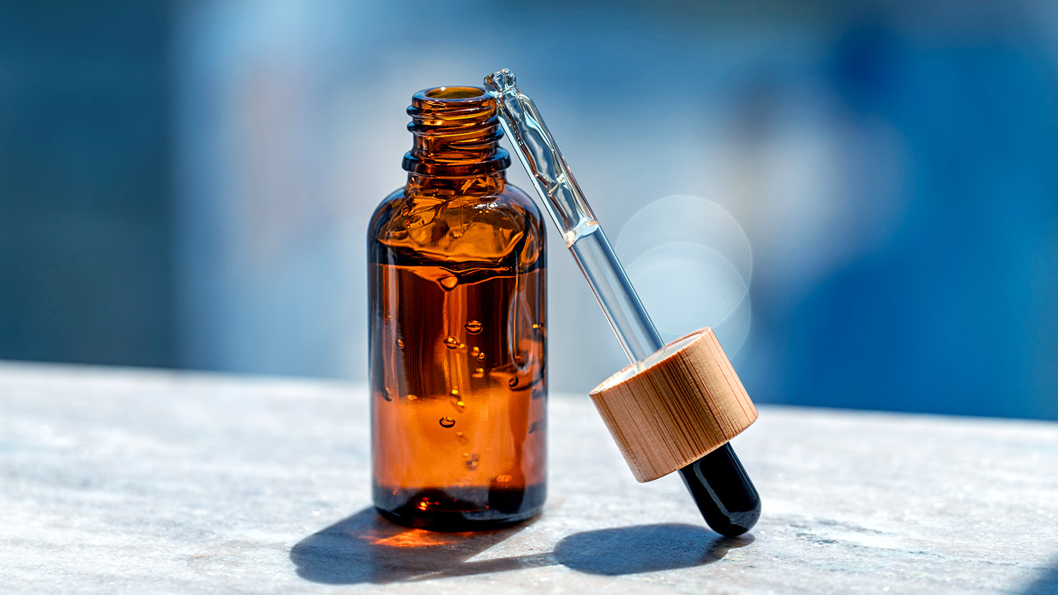 A close-up shot shows a brown glass bottle of essential oil with a dropper lying next to it. 