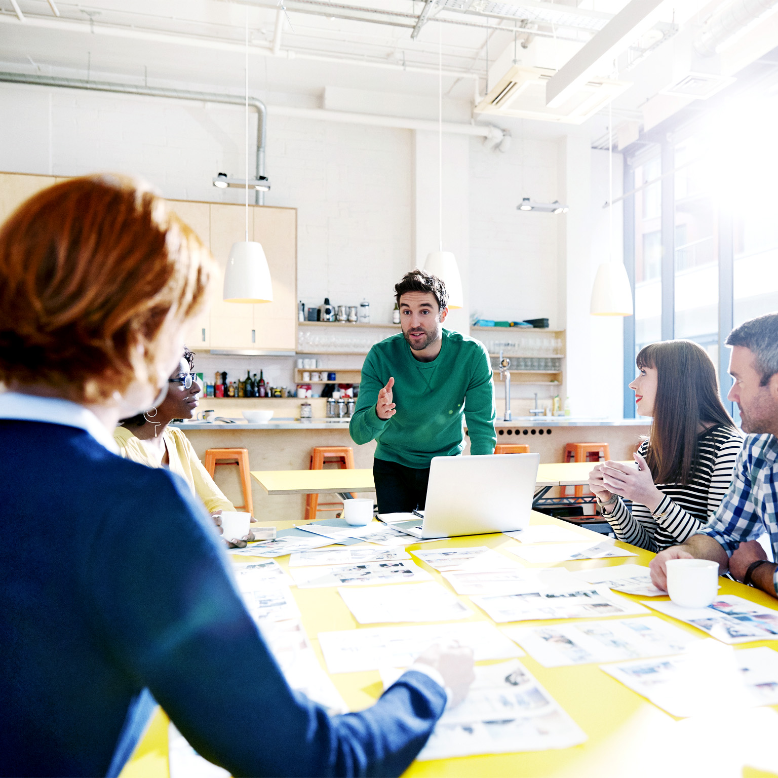 A team meeting at which five colleagues are reviewing creative ideas.