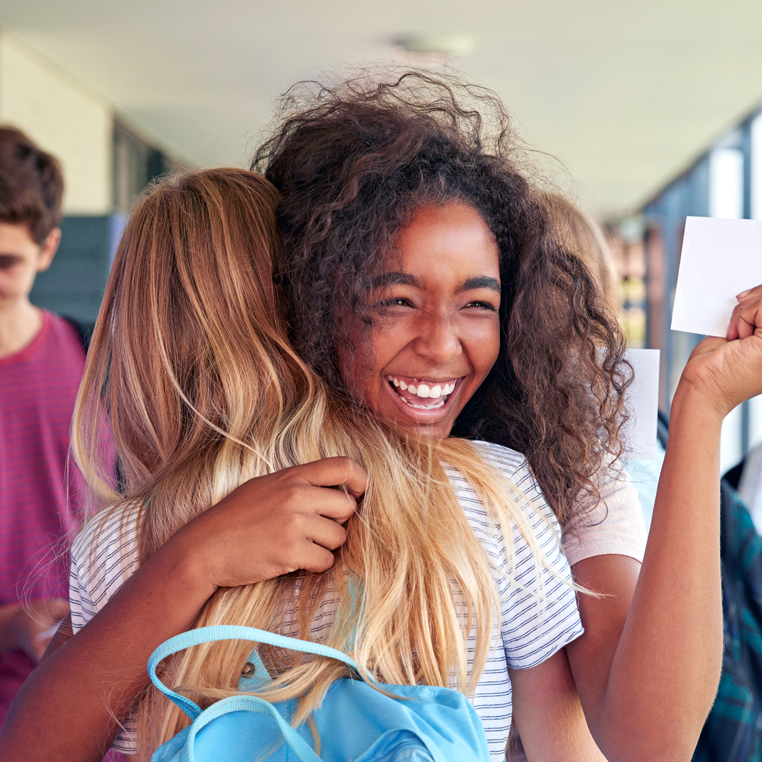 Two girls celebrating exam results in school corridor