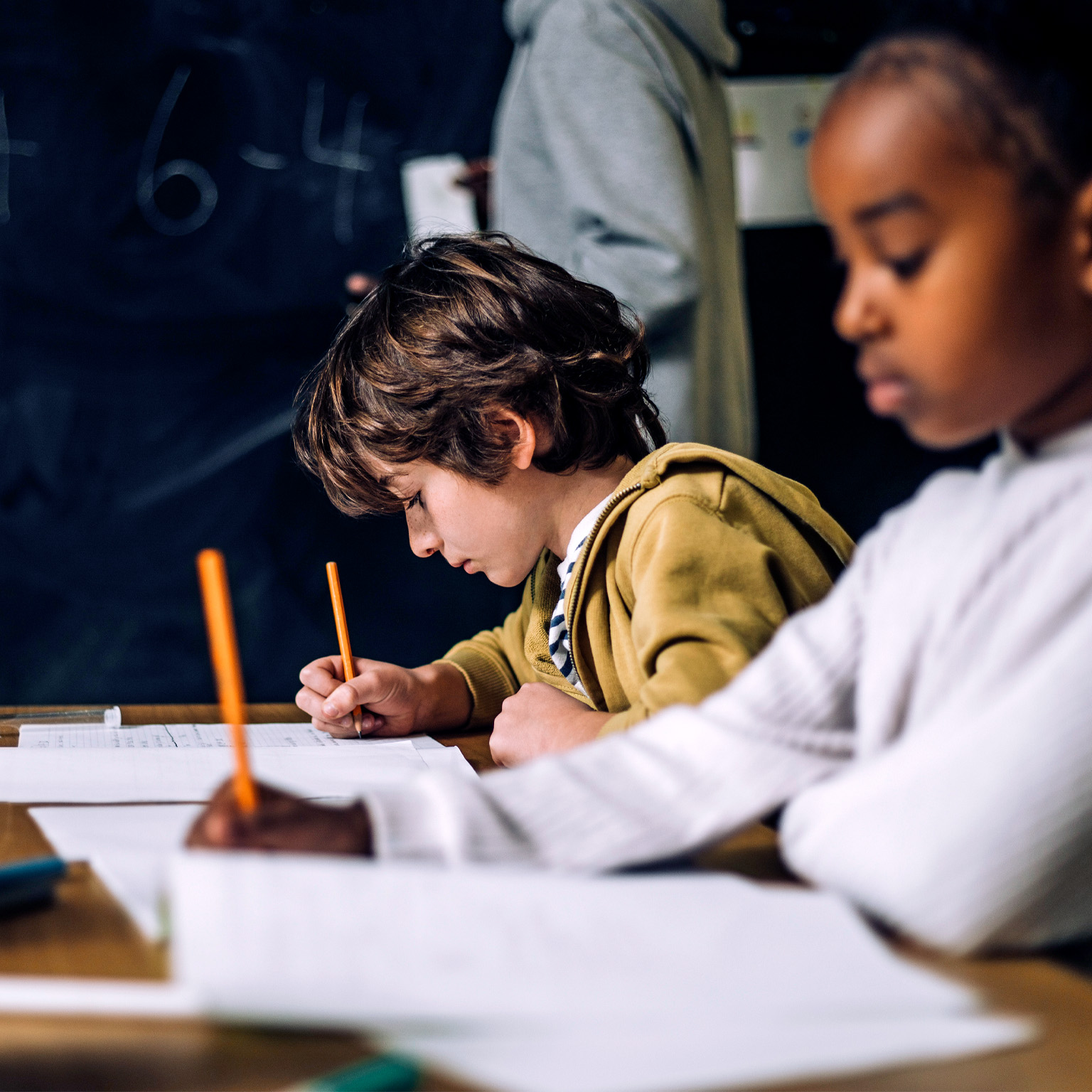 Smiling boy talking to female student while sitting in classroom