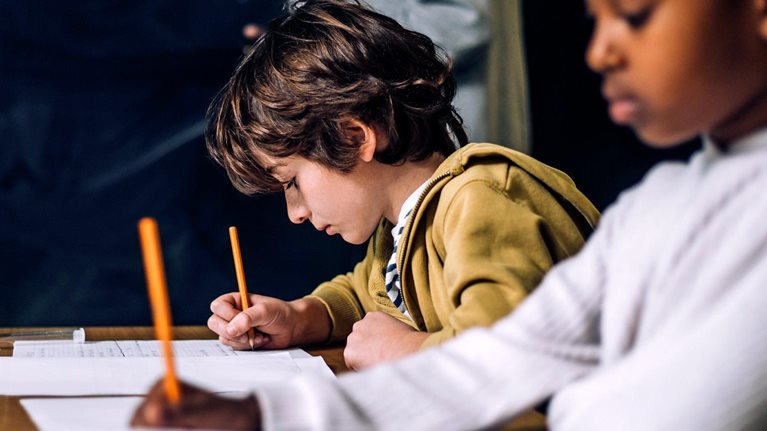 Smiling boy talking to female student while sitting in classroom