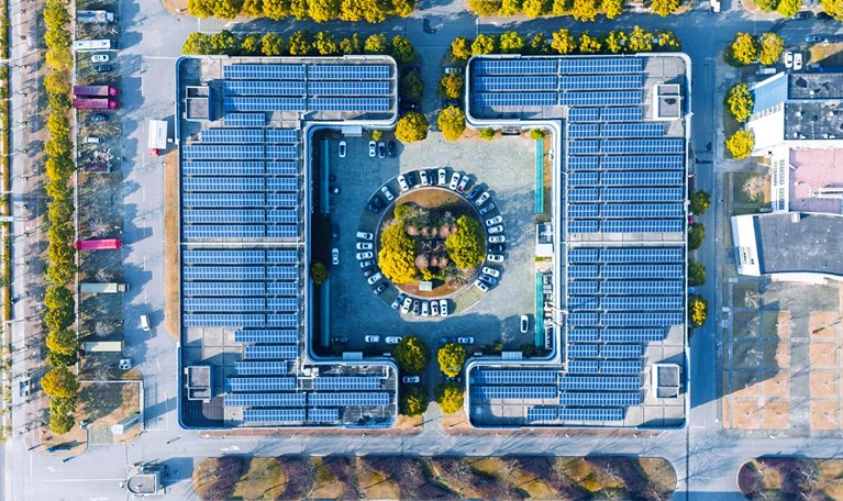 Aerial view of solar panels covering the top of a modern office building.