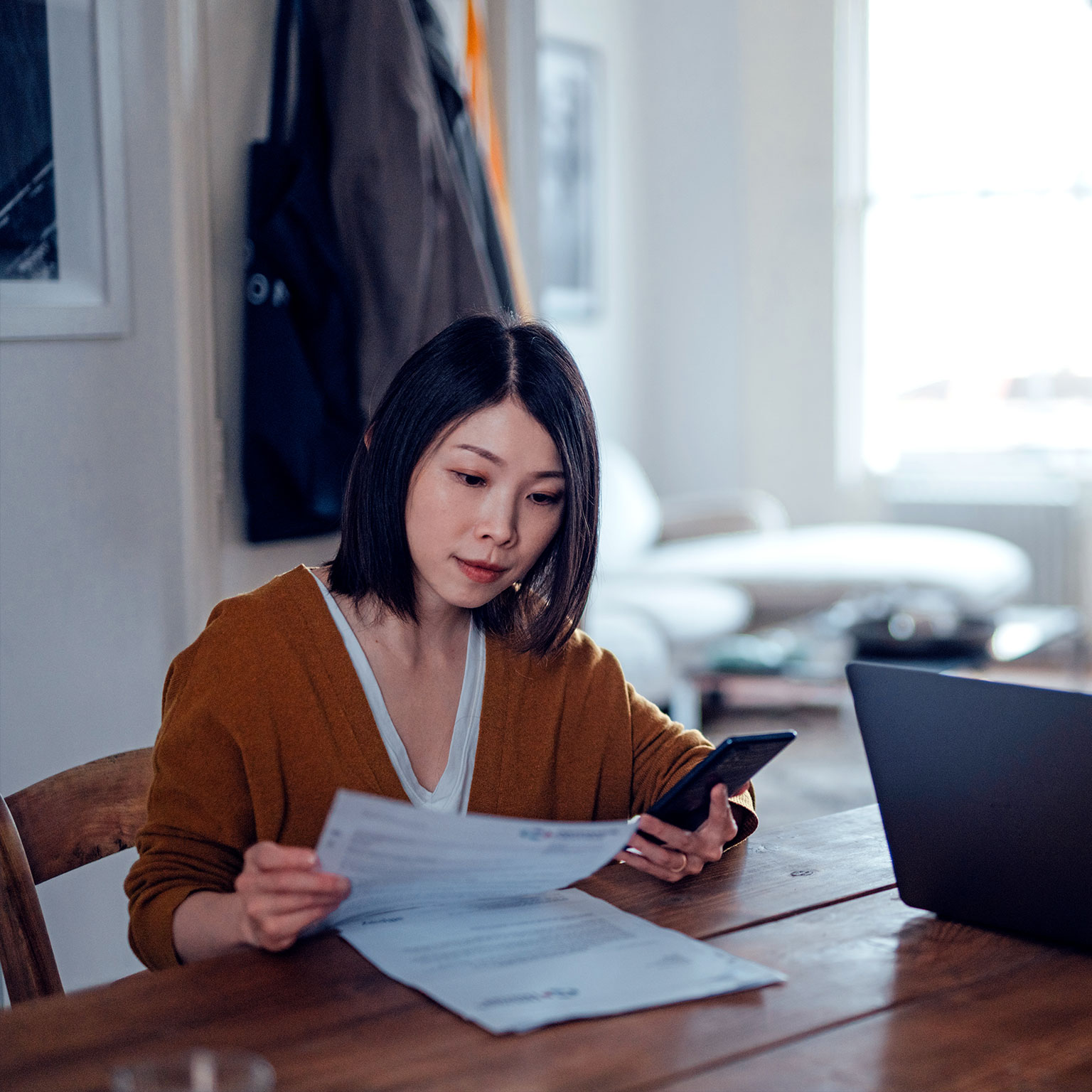 A man and woman handling forms with a phone and laptop on hand