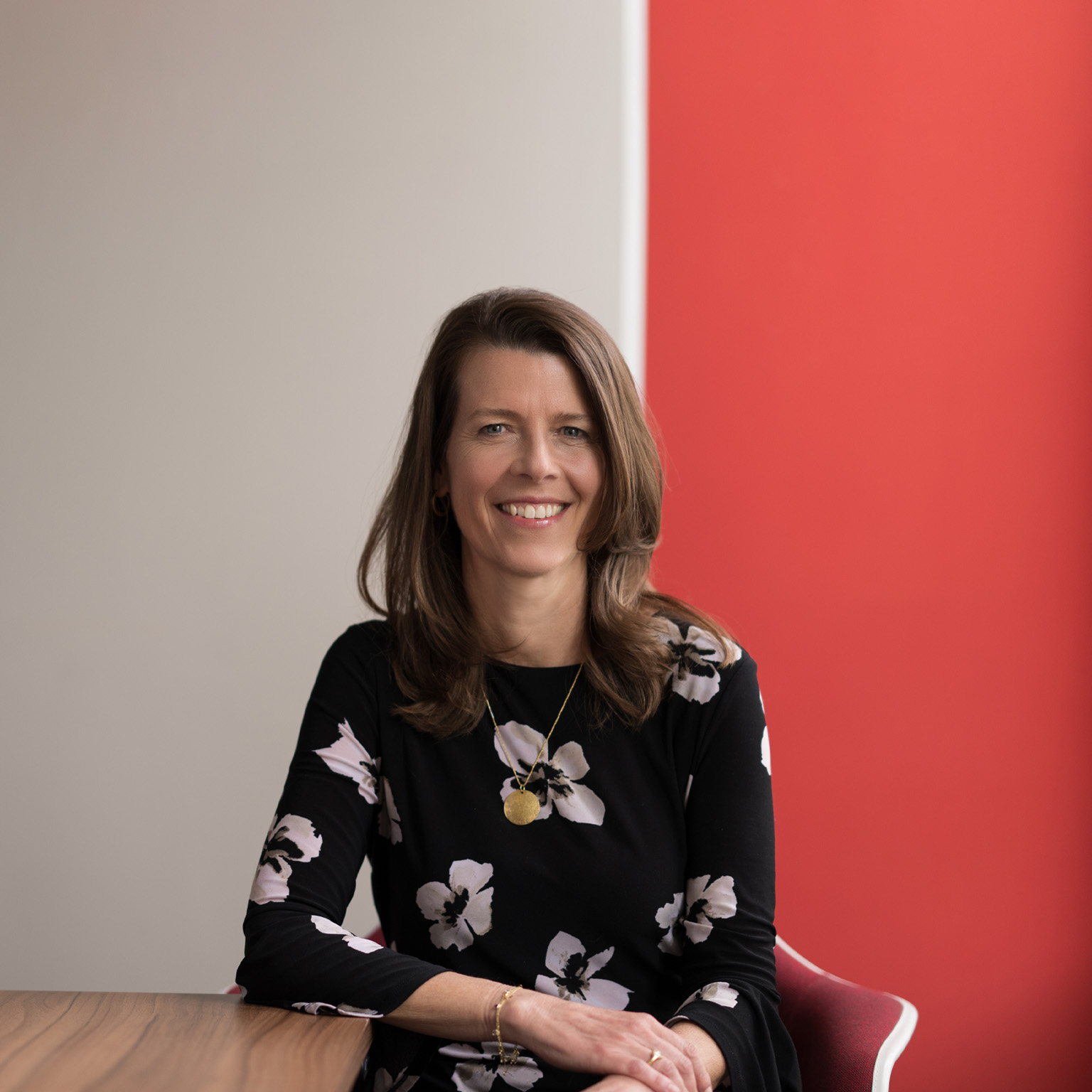 Portrait of a smiling Barbara Karuth-Zelle resting her elbow on a wooden table.
