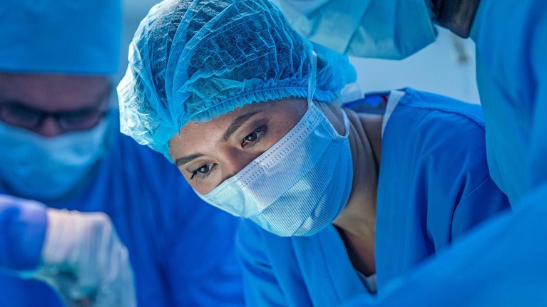 Healthcare workers performing surgery on patient in operating room.