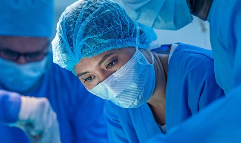 Healthcare workers performing surgery on patient in operating room.
