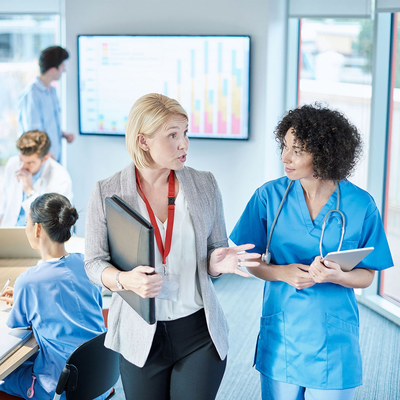 A businesswoman meets with a doctor prior to sitting at a boardroom meeting in a hospital