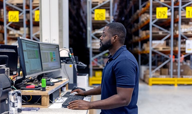 Man working on computer in large factory warehouse