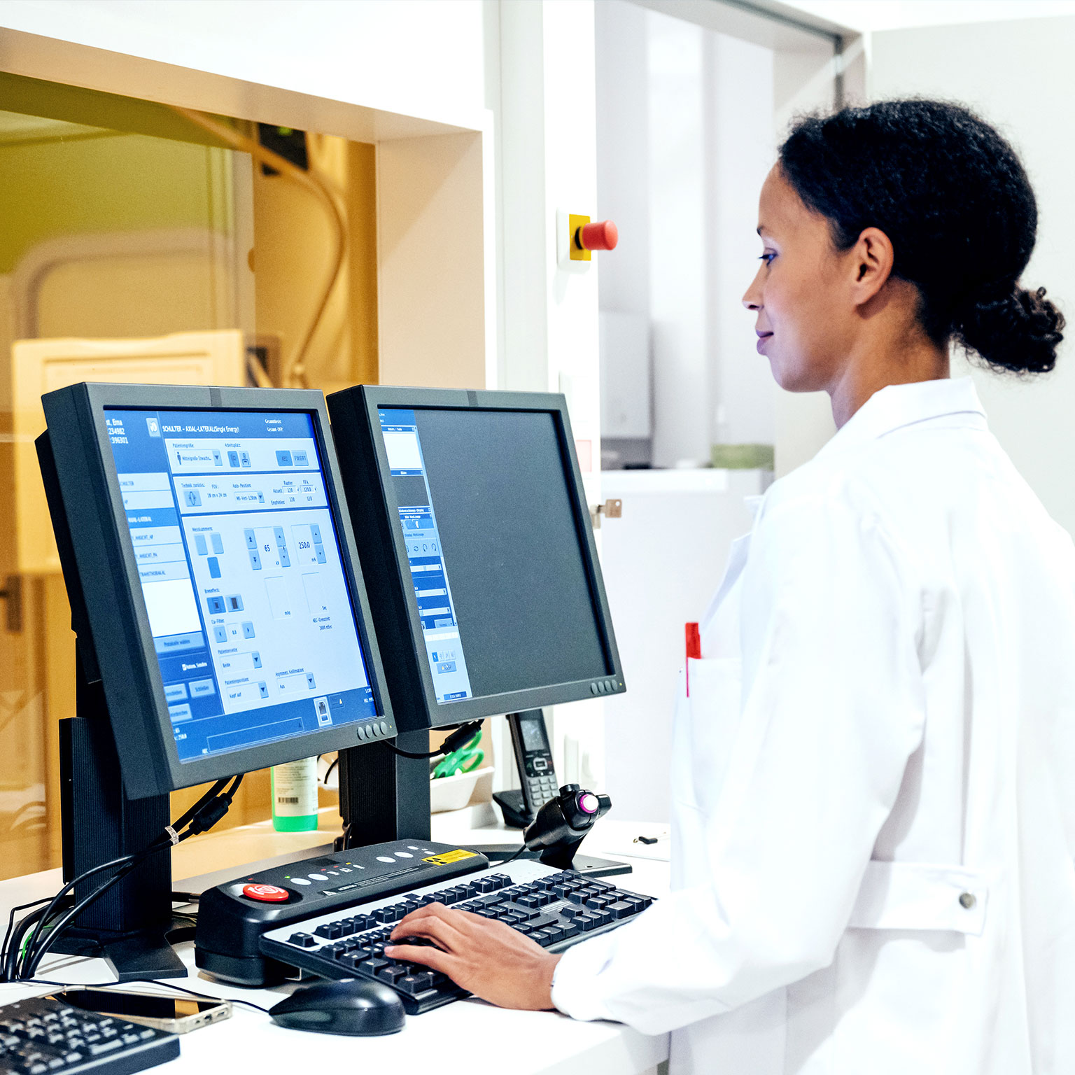Woman in white overcoat working on desktops