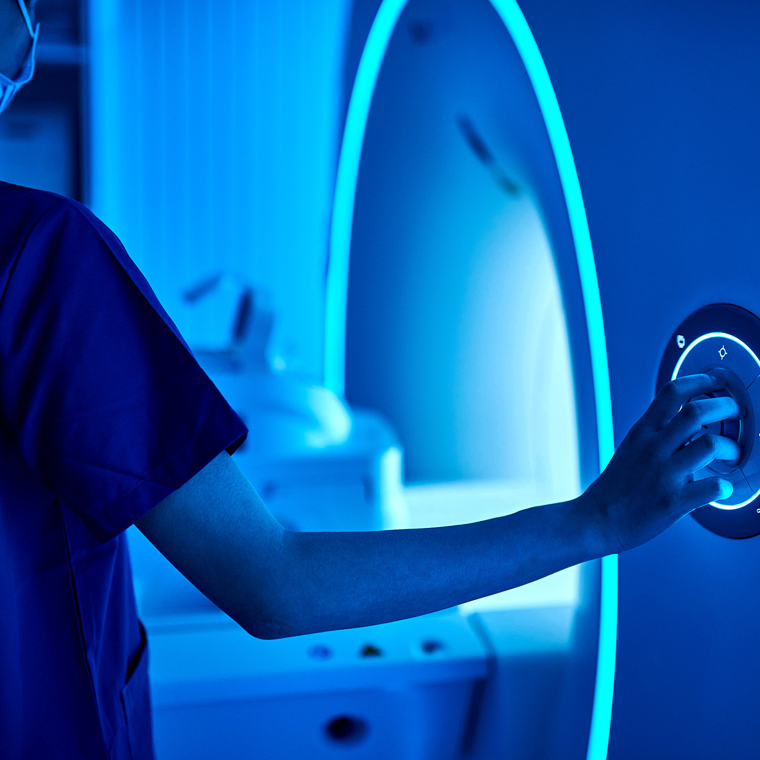 A healthcare professional adjusts the controls of a medical imaging machine.