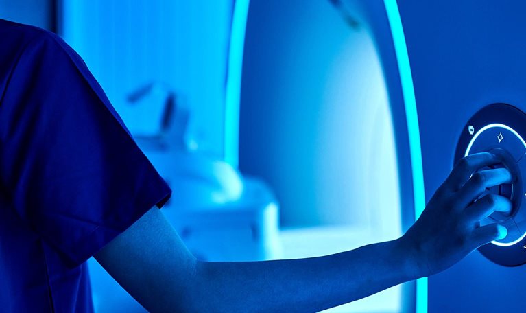 A healthcare professional adjusts the controls of a medical imaging machine.