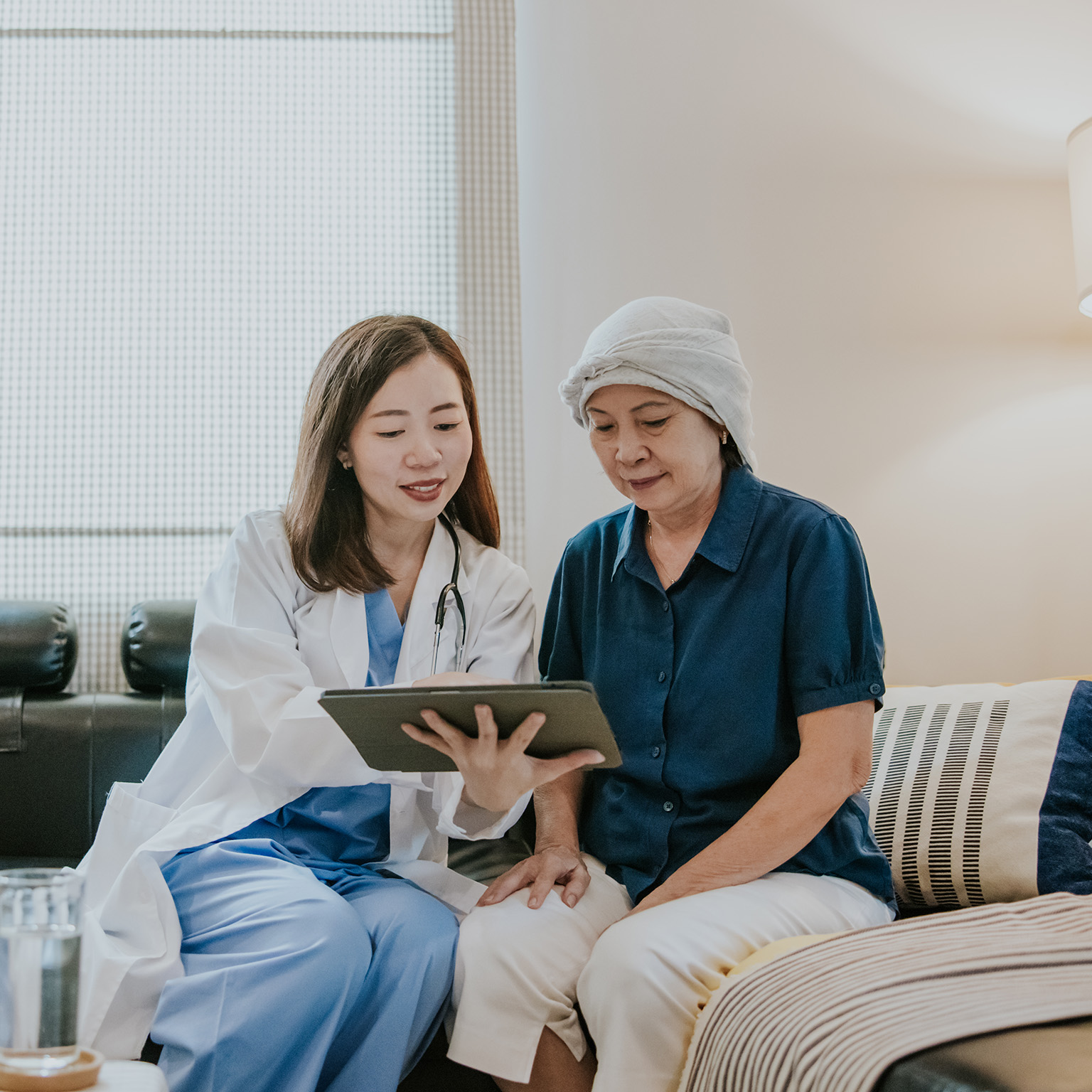Young female doctor use tablet to explain her senior patient about cancer and medication for next step