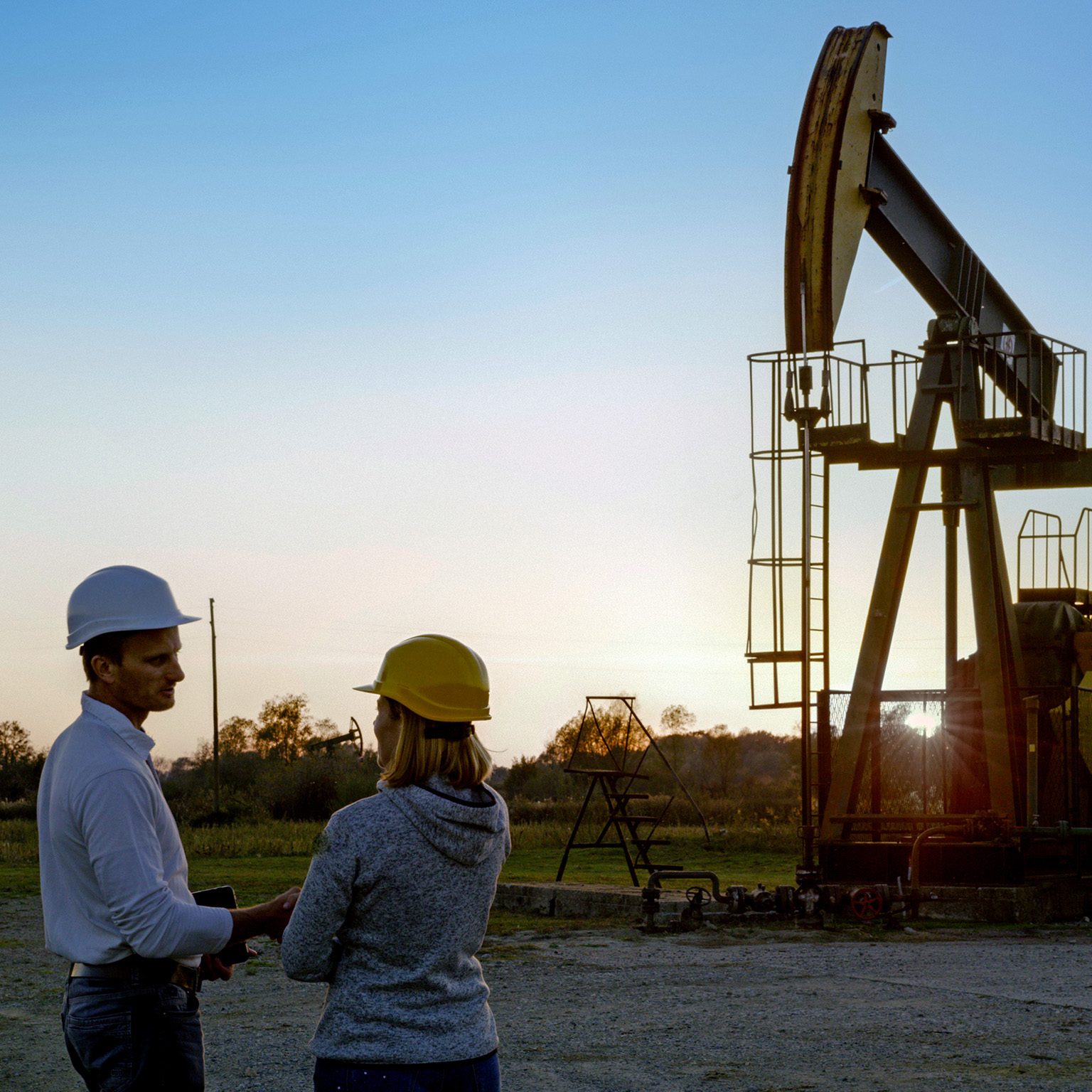 Two engineers standing near a pumpjack