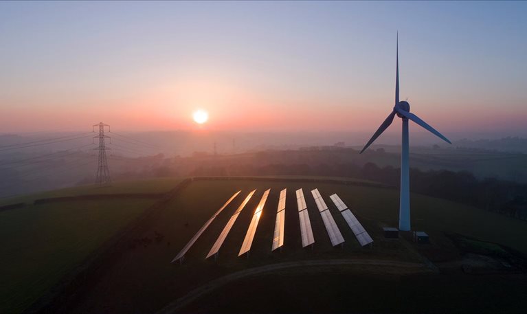 Solar panels and wind turbines in field - stock photo