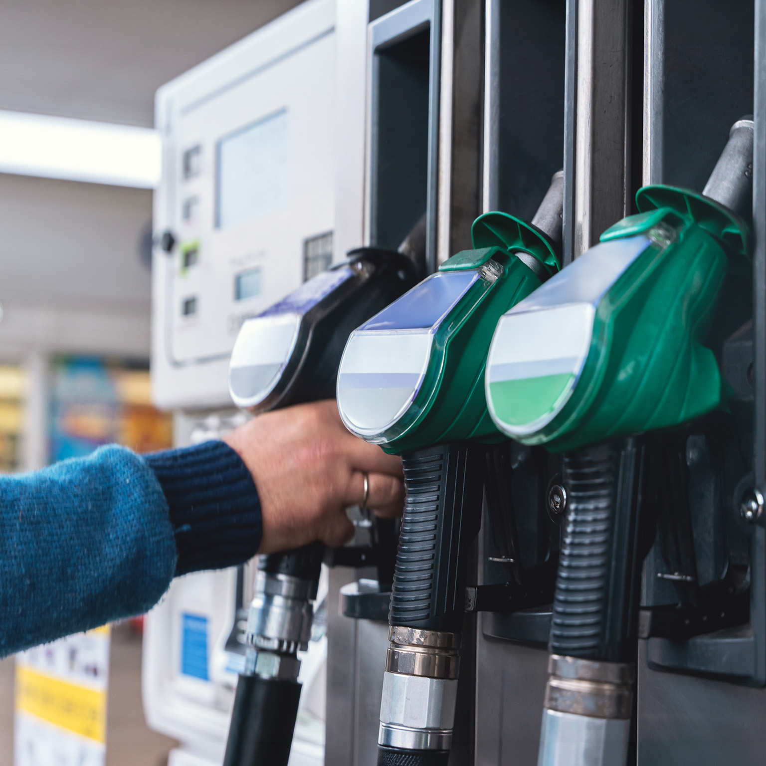 Refueling at a modern gas station with green fuel pumps and a customer filling their vehicle in a well-lit, organized space during daytime