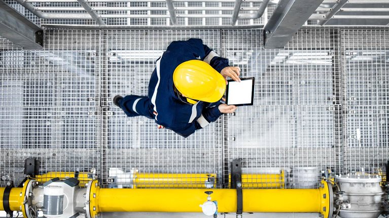 Top view of petroleum refinery worker walking by gas pipes and checking production.