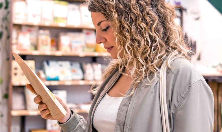 Woman looking at food products on the shelf of a local organic grocery store