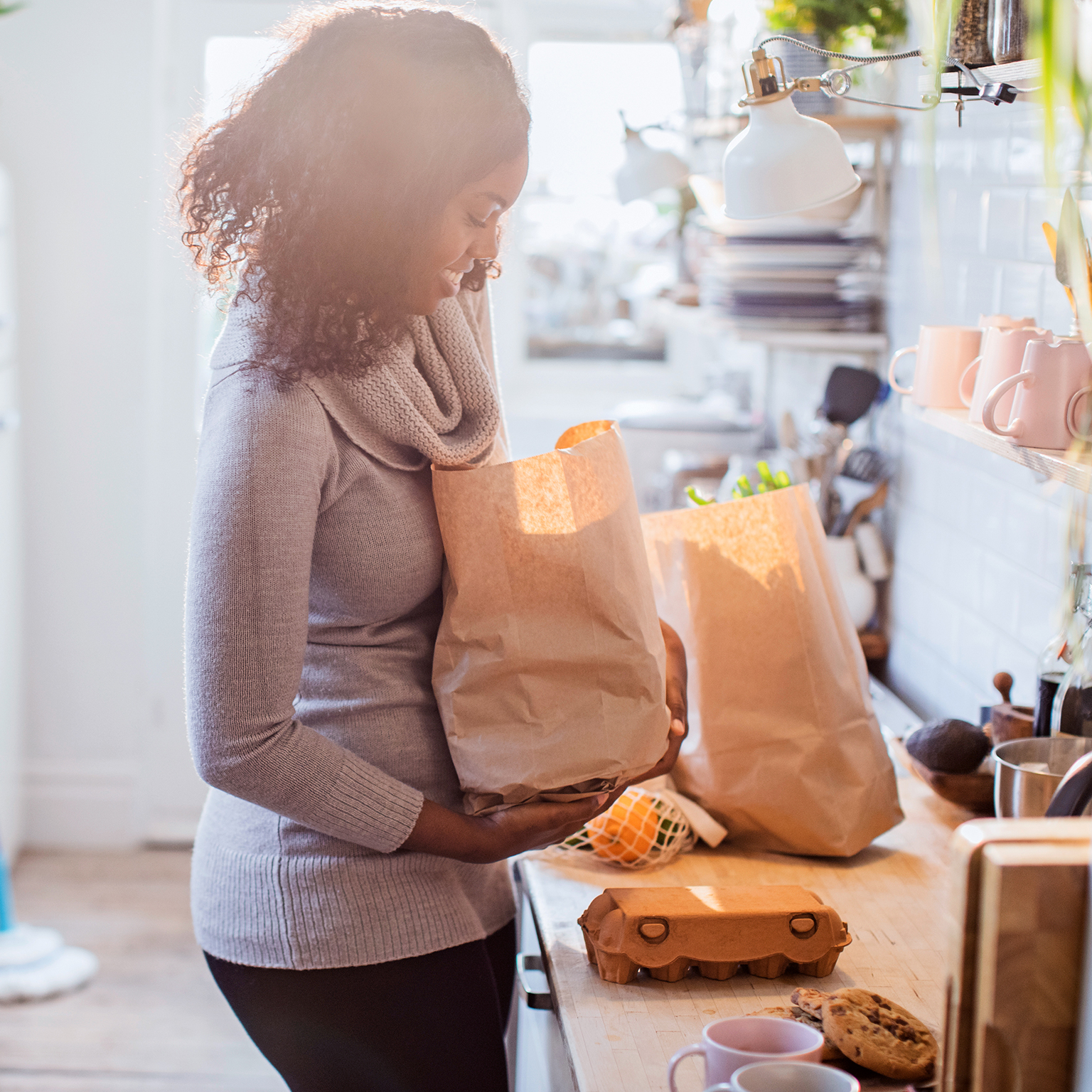 Mother and daughter unloading groceries in sunny kitchen - stock photo