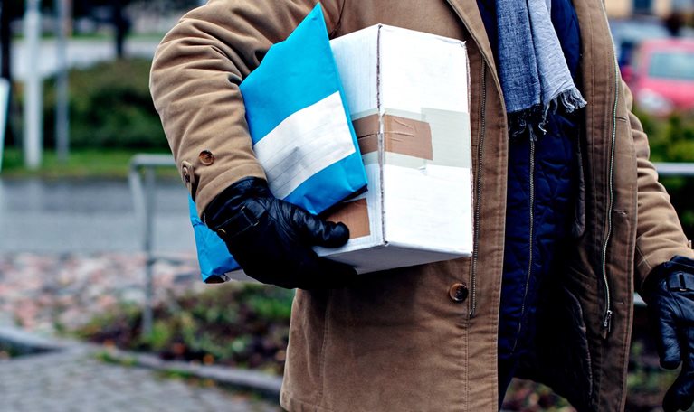 Midsection of senior man with package walking by sidewalk during winter - stock photo