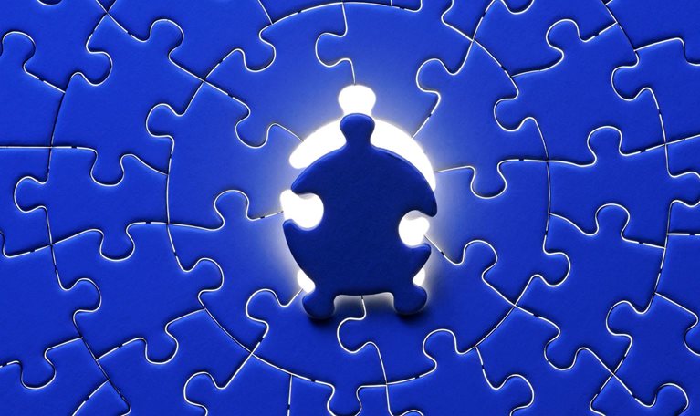 Blue final piece of the jigsaw with light from behind.