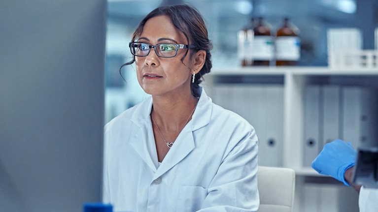 Two scientists working together on a computer in a lab focused on finding the right results