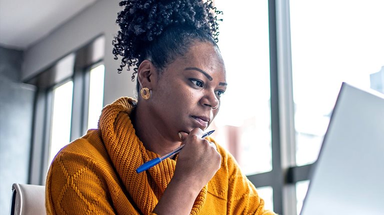 Black woman working from home office and looking pensively at her computer screen