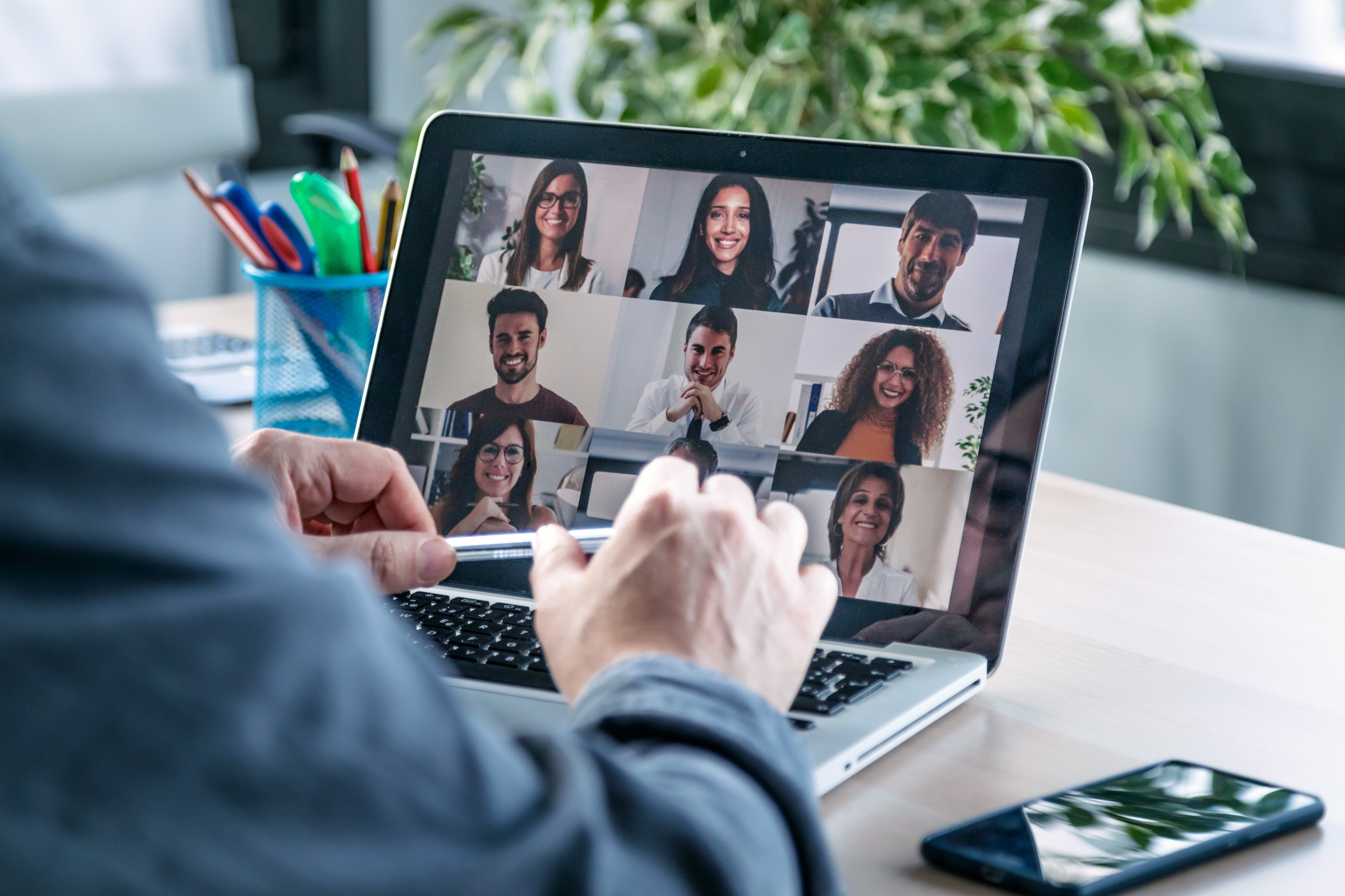 Male employee speaking on video call with diverse colleagues on online briefing with laptop at home.
