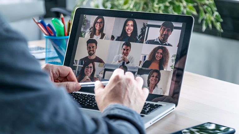 Male employee speaking on video call with diverse colleagues on online briefing with laptop at home.