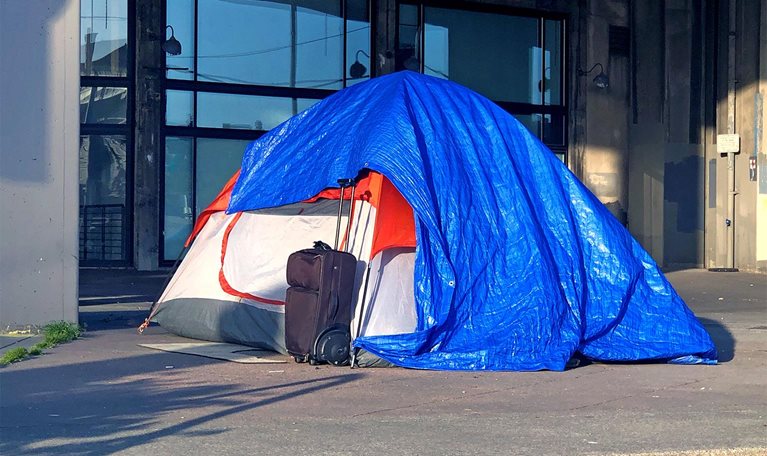 Tarped tent and suitcase on a city sidewalk