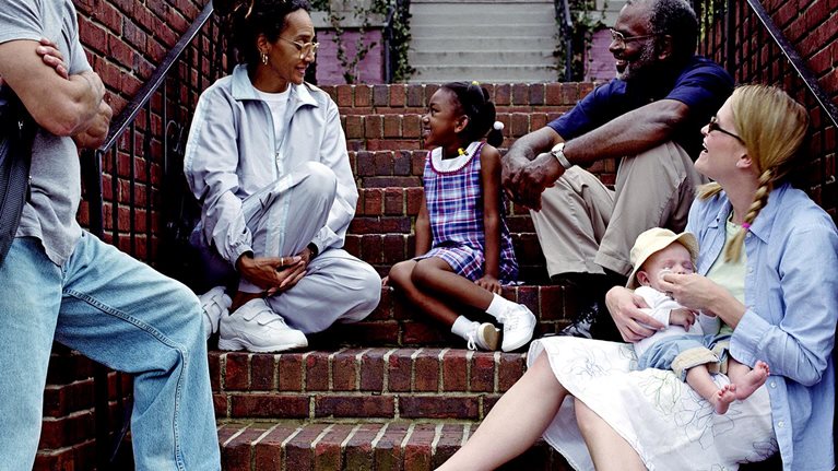 Men, women, and children catching up at the staircase to a home