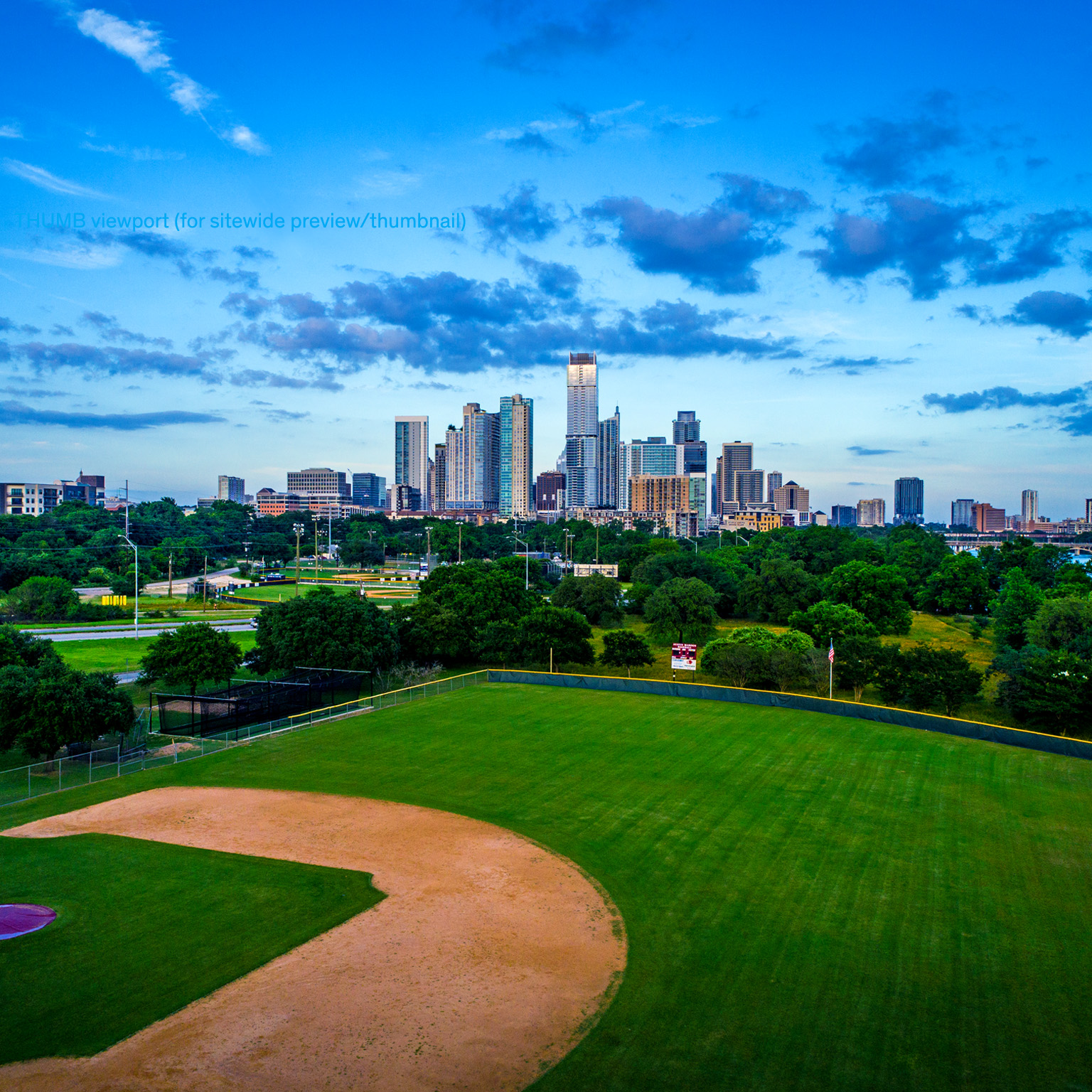 Wide angle view of the skyline with tall towers and green grass and a walkway