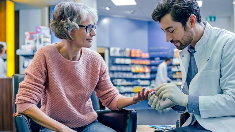 Pharmacist measuring blood sugar of customer in pharmacy