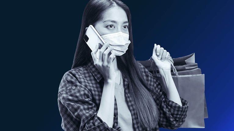 Asian woman with shopping bags and mask on mobile phone