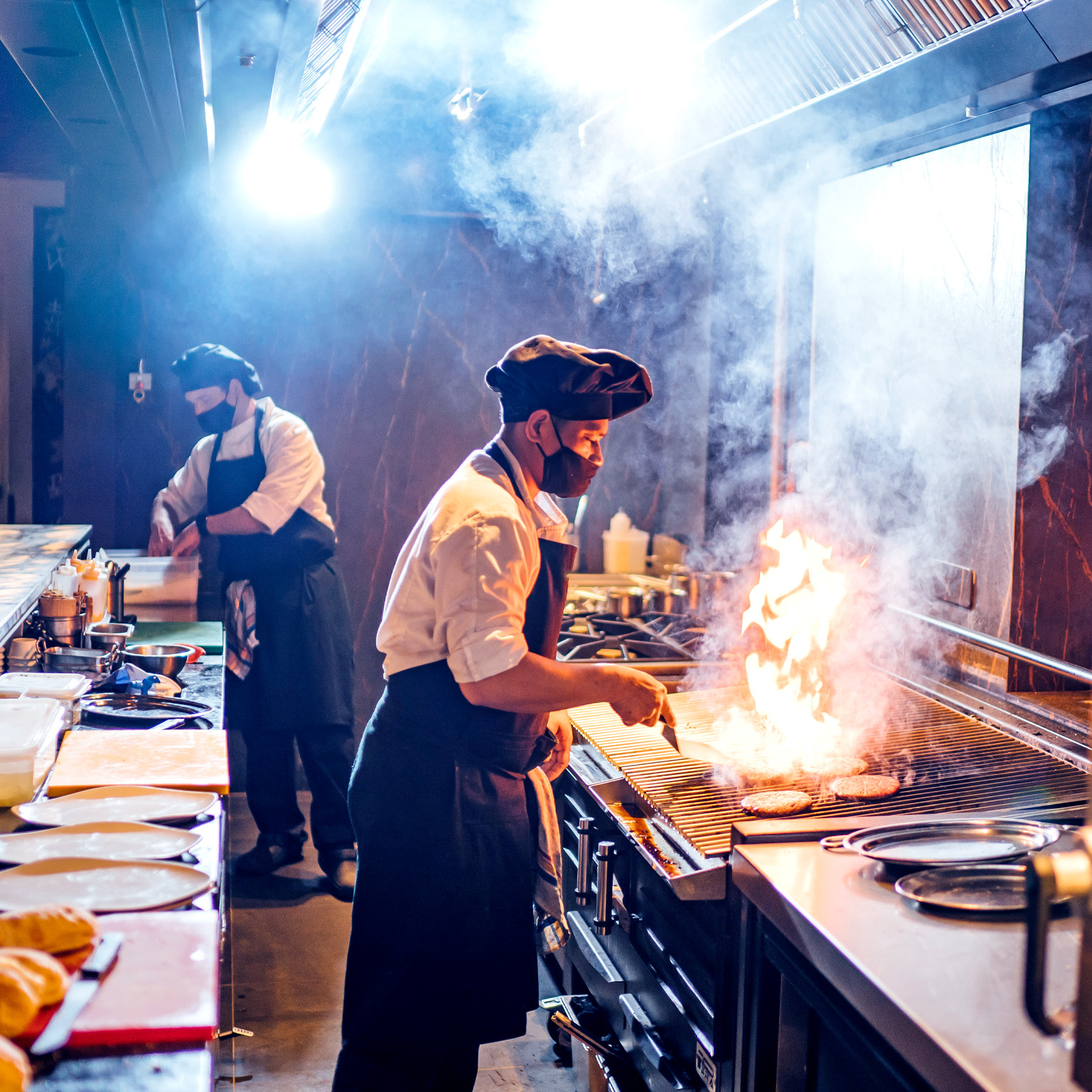 Chefs wearing protective face masks preparing a dish in restaurant kitchen