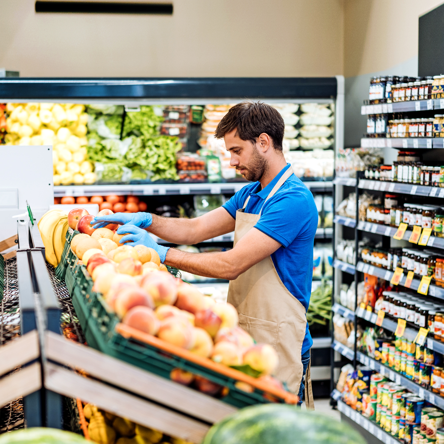 Employee in supermarket arranging fresh fruit