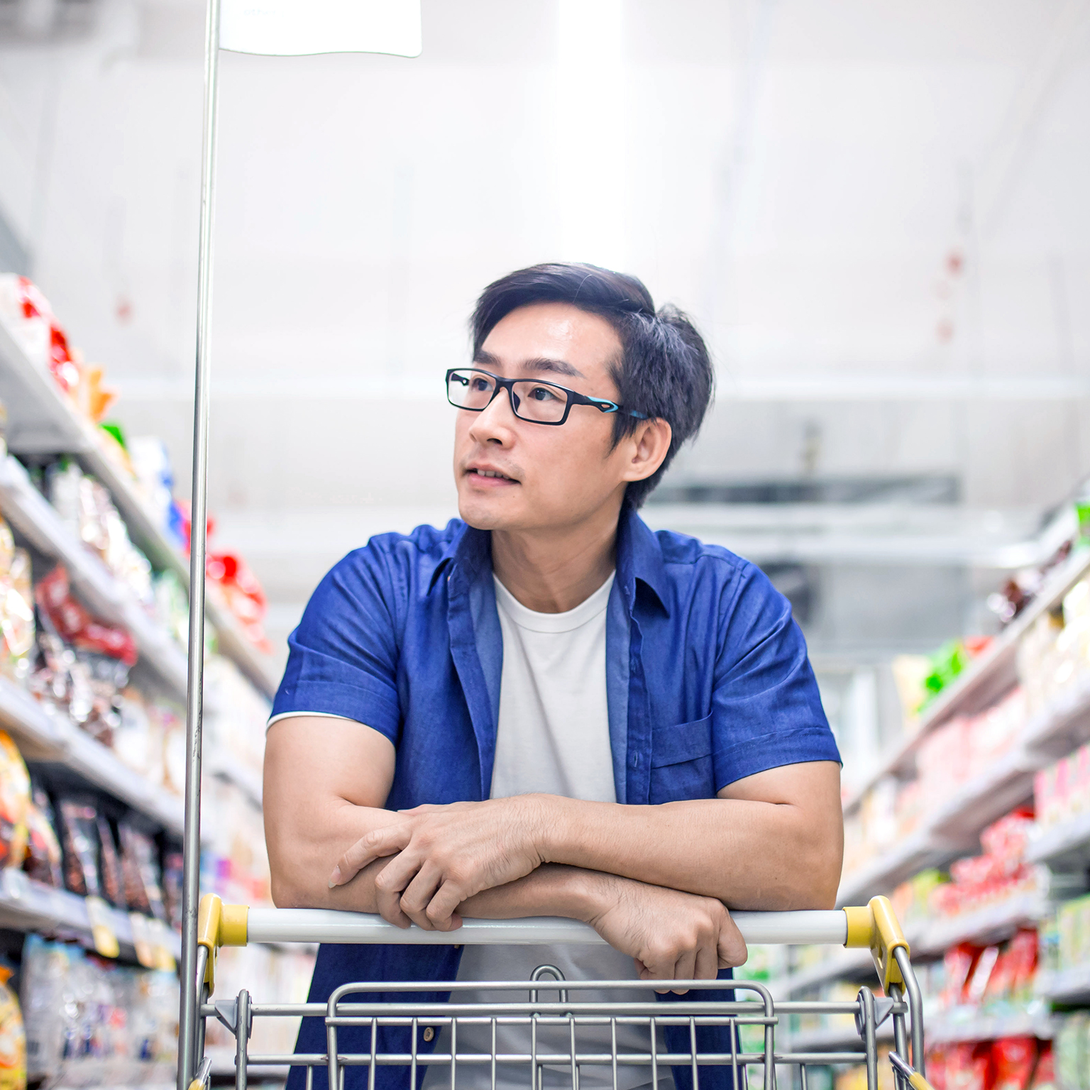 An Asia mature man pushes shopping cart and browses for products in groceries shop
