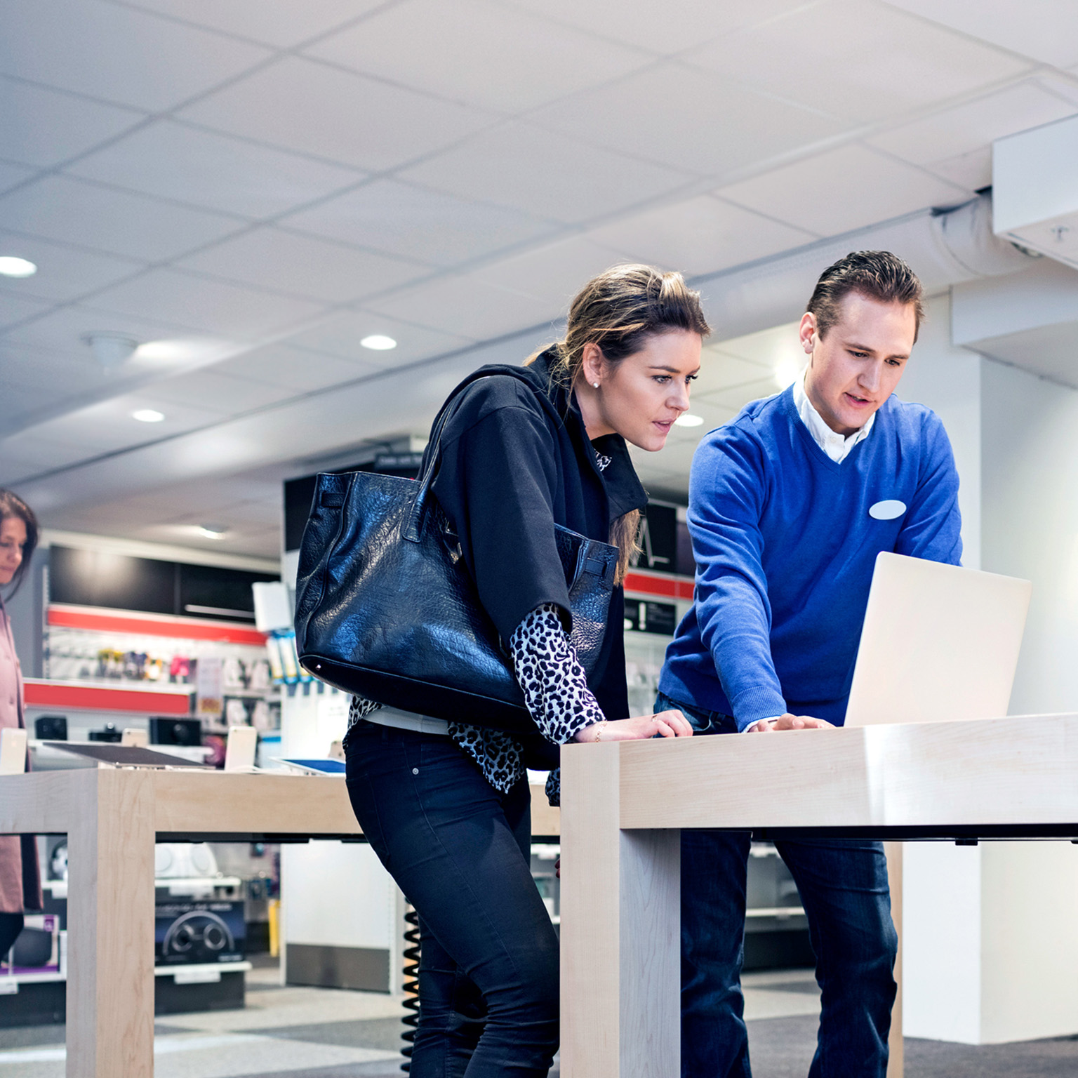 Salesman assisting female customer in buying laptop at store