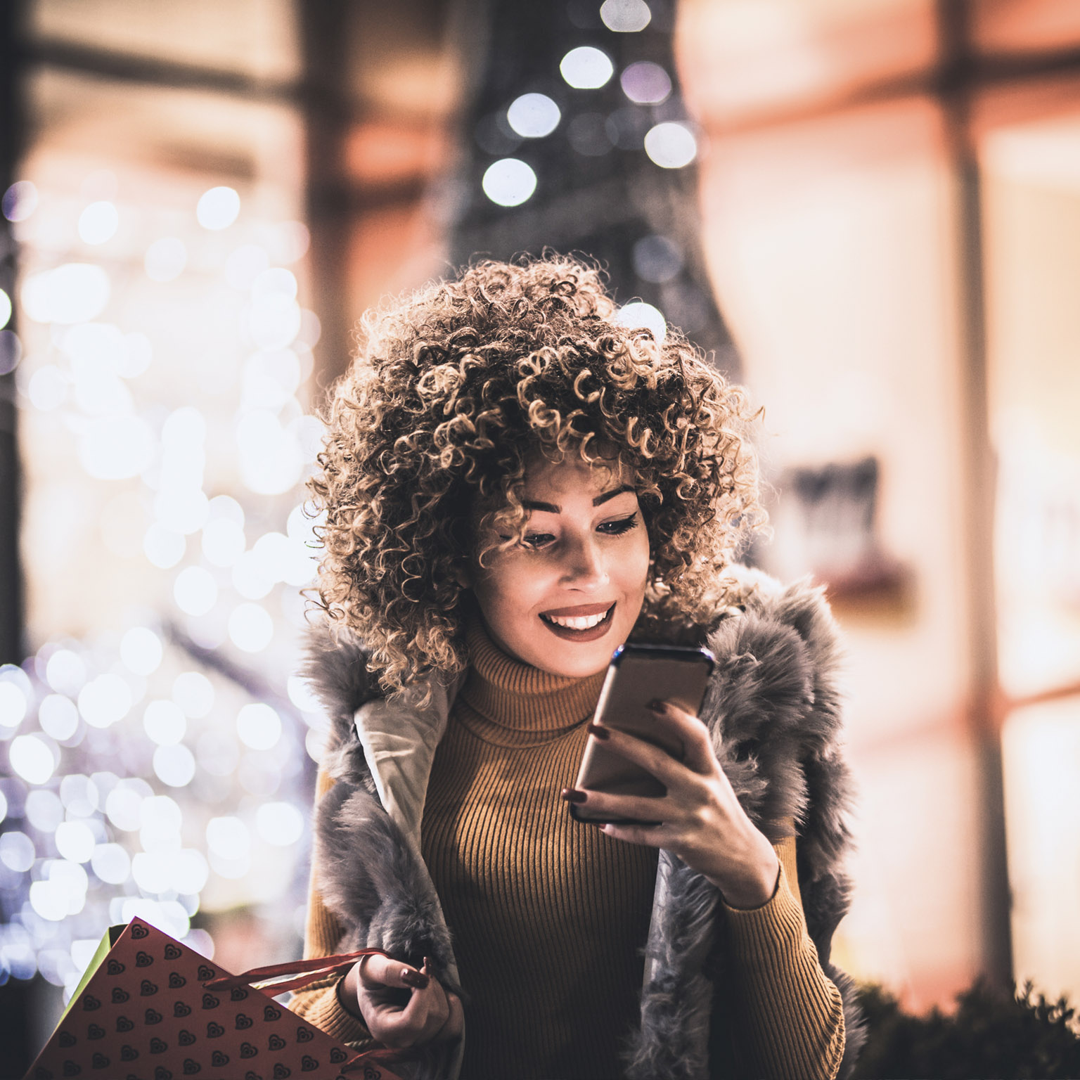 Woman using smartphone and holding shopping bag