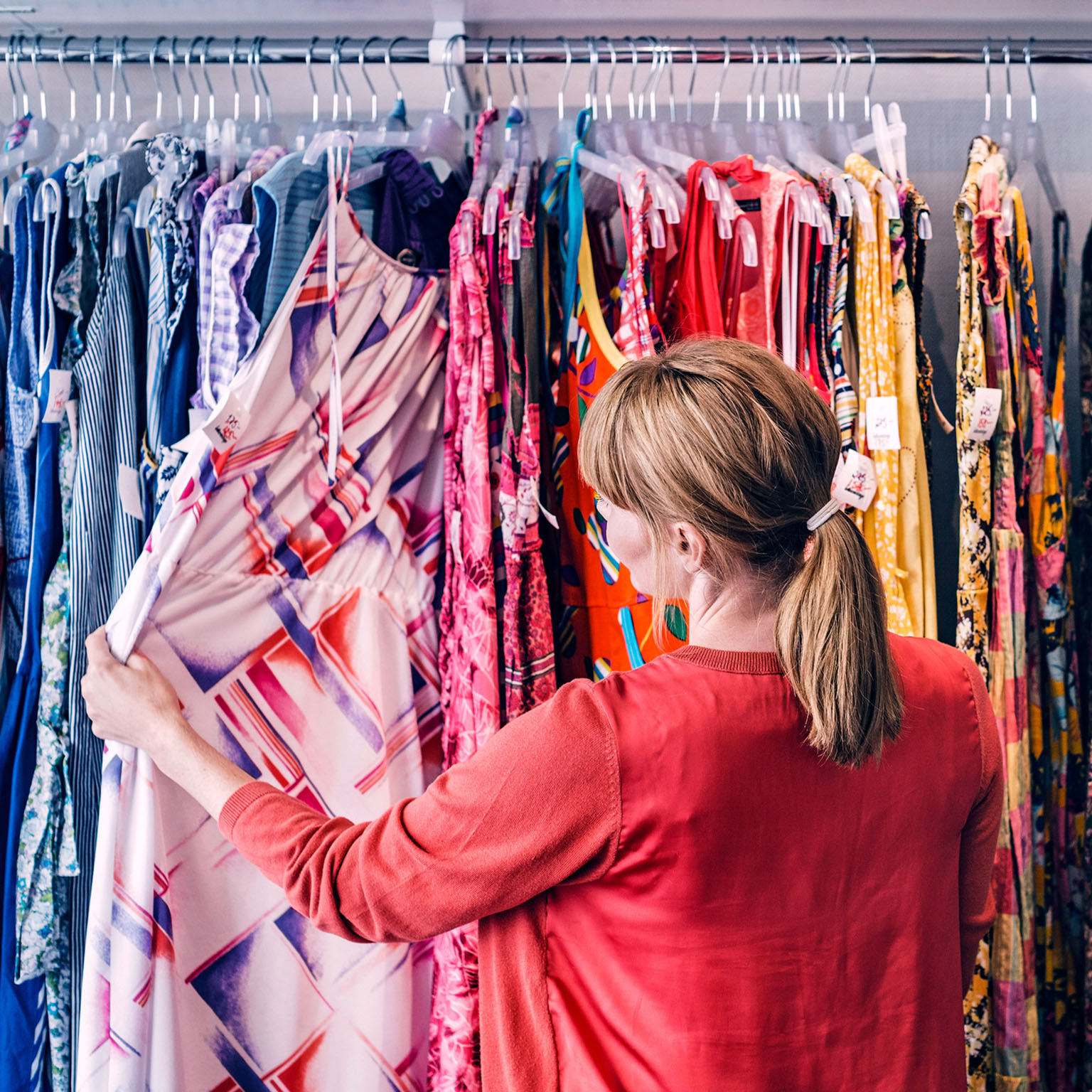  Woman looking at dress hanging on rack while standing in store