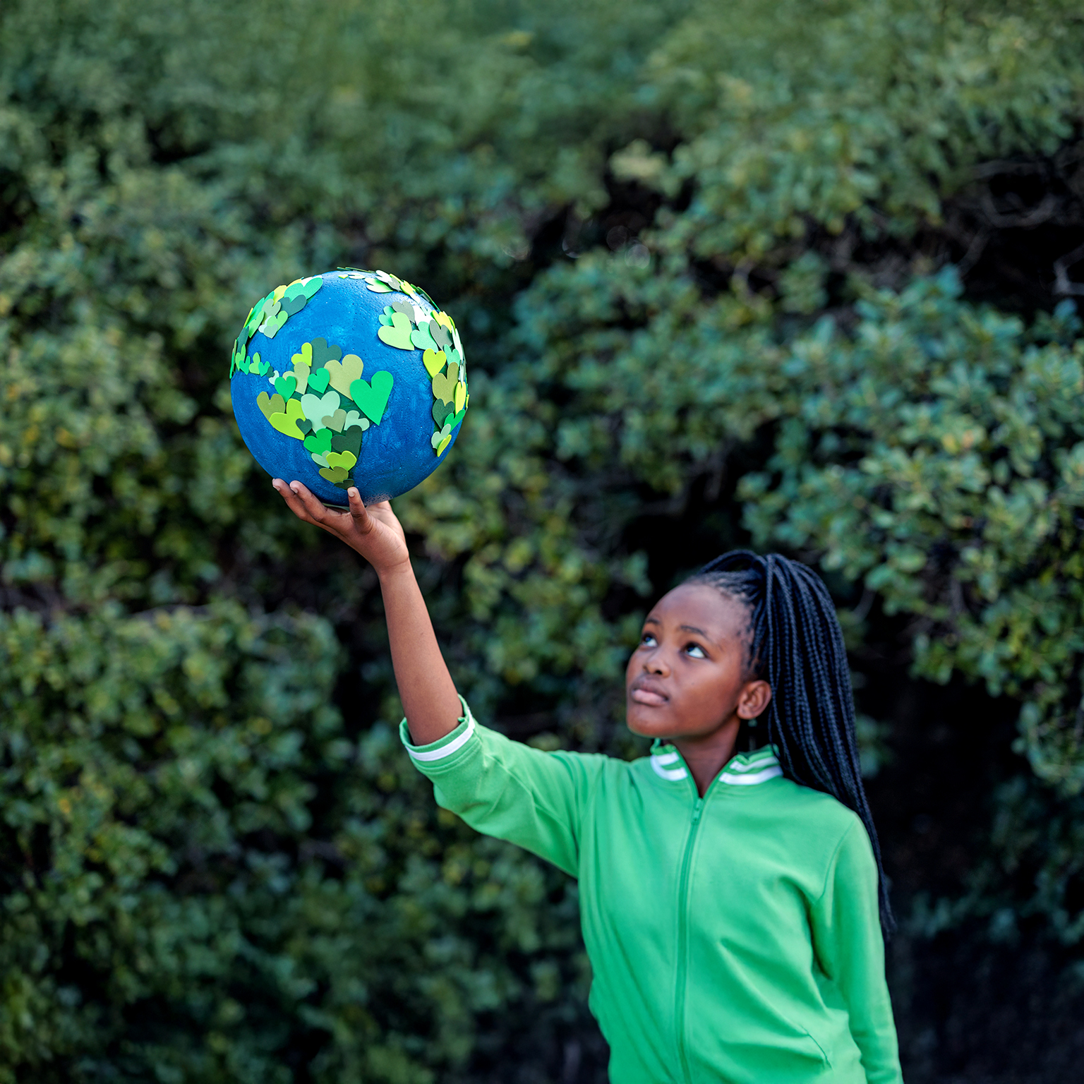 Young African girl holding up a homemade globe of green heart shapes