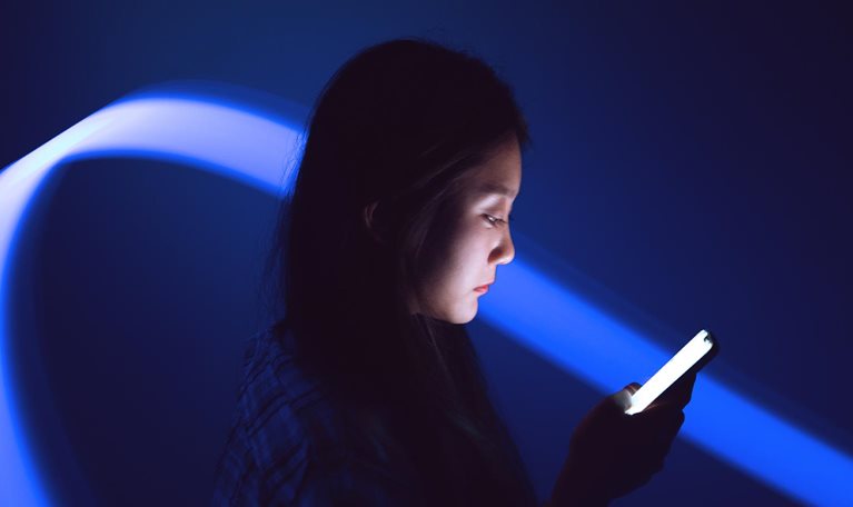 Young Asian woman using smartphone on the holographic background. Metaverse and AI - stock photo