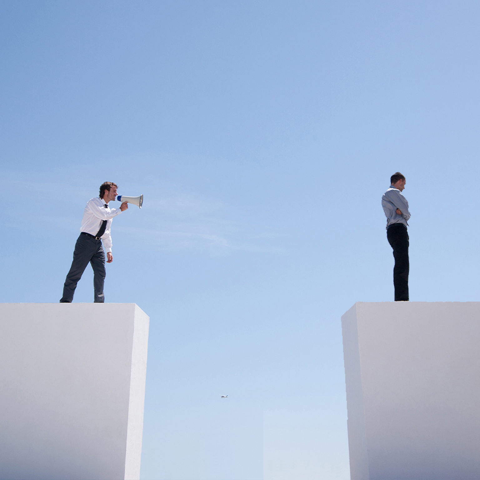Businessman with megaphone on wall shouting at businessman on wall with gap